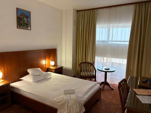 a hotel room with a bed and a window at Hotel Emma West in Craiova