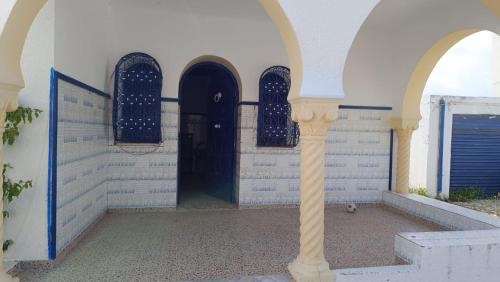 a building with three arched doors and a column at Charmante maison plage in Soliman