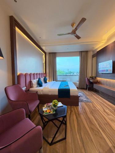 a hotel room with a large bed and chairs at The Infinity Hotel in Kānpur