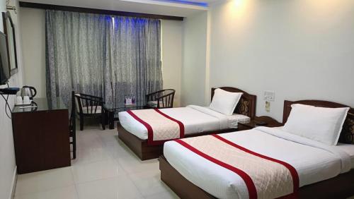 a hotel room with two beds and a window at Bodhgaya Regency Hotel in Bodh Gaya