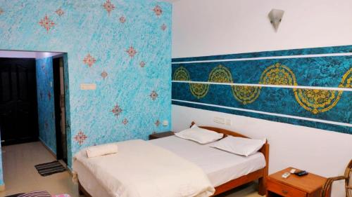 a bedroom with two beds and a blue wall at Peninsular wood Resort in Thattakād