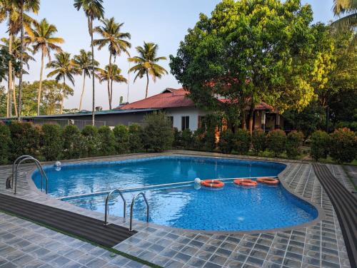 a swimming pool in a resort with palm trees at Peninsular wood Resort in Thattakād