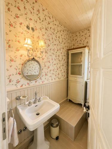 a bathroom with a sink and flowers on the wall at Villa AVRA in Drama