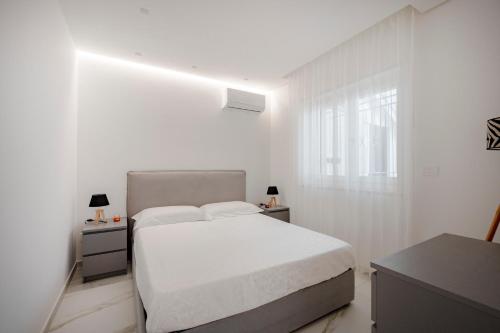 a white bedroom with a bed and a window at GuestHost - Lume di Mare in Faccia di Trippa