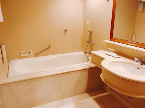 a bathroom with a bath tub and a sink at Han Hsien International Hotel in Kaohsiung