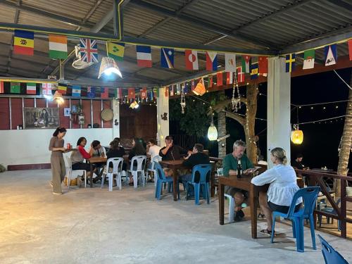 a group of people sitting at tables in a restaurant at PAKBENG SUNSET DORM Room in Pakbeng