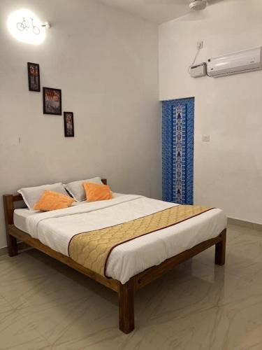 a bedroom with a bed with orange pillows on it at Jo Inn Beach View Guest House in Kuilapayam