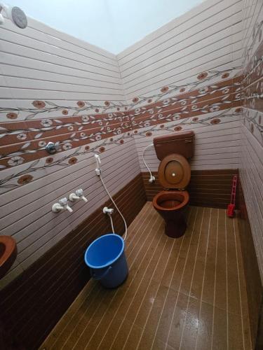 a bathroom with a toilet and a blue bucket at Jo Inn Beach View Guest House in Kuilapayam