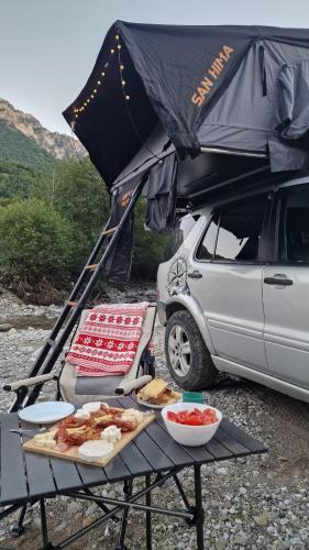 a picnic table in front of a car with food on it at car camping rental in Shkodër