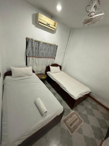 a room with two beds in a room with a fan at PAKBENG SUNSET DORM Room in Pakbeng