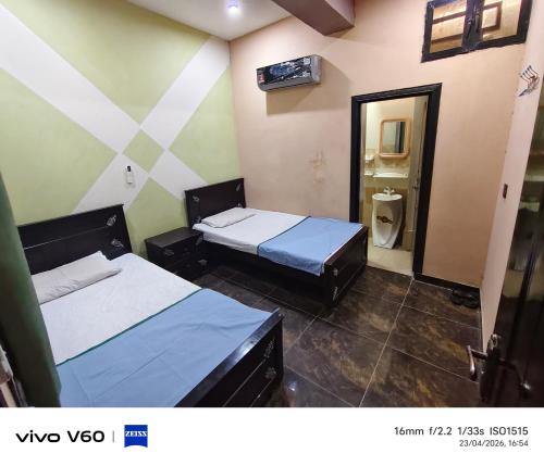 two beds in a room with a bathroom at Al Qadir Residence in Multan