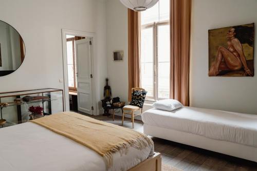 a bedroom with two beds and a chair and a mirror at Les Chambres du Vaudeville in Brussels