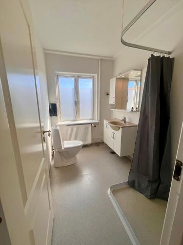 ein Badezimmer mit Toilette, Waschbecken und Fenster in der Unterkunft Sverres Hotel in Rønne