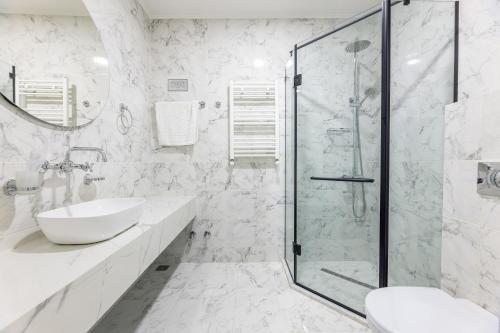 a white bathroom with a shower and a sink at Boutique Hotel Manufactura in Tbilisi City