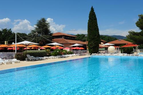 uma grande piscina com cadeiras e guarda-sóis em Village Vacances La Manne em Bormes-les-Mimosas