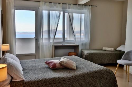 a bedroom with two beds and two large windows at Hôtel restaurant Le Belvedere De Coti in Coti-Chiavari