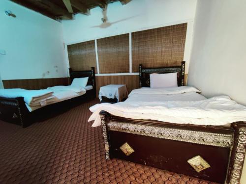 two twin beds in a room with at Hunza Backpackers Inn in Hunza Valley