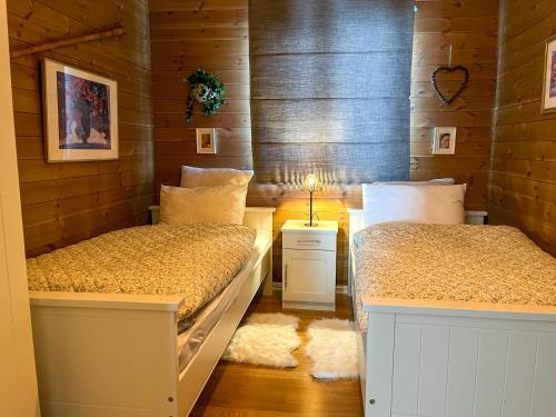 two beds in a room with wooden walls at Grønebakkins smørøye in Beitostøl
