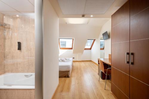 a bathroom with a tub and a bed and a sink at Hotel Longoria Plaza by Pandora Hoteles in Oviedo