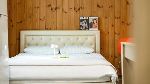 a bedroom with a white bed with a wooden wall at Gapyeong Haneuldari pet pension in Gapyeong
