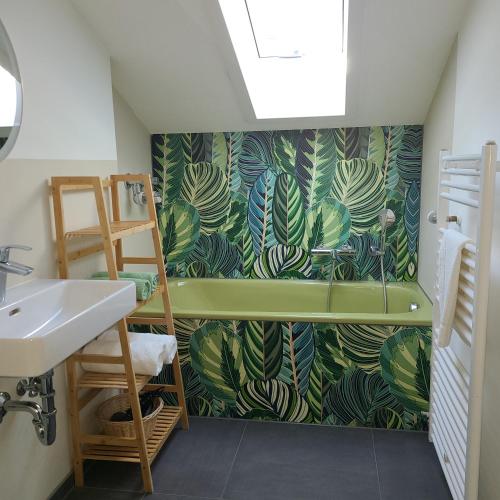 a bathroom with a sink and a green plant wallpaper at BergLiebe in Unterammergau