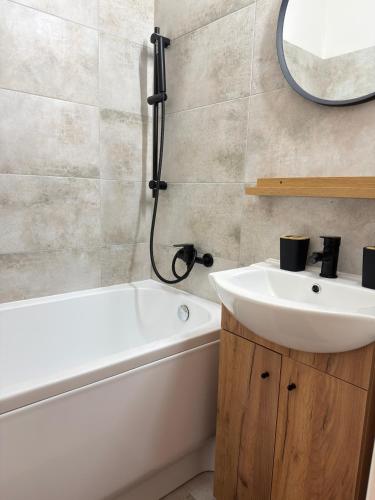a bathroom with a sink and a tub and a mirror at Apartmán Športovcov in Dolný Kubín