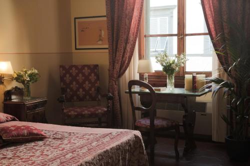 a bedroom with a bed and a table and a window at Hotel Villa Liana in Florence