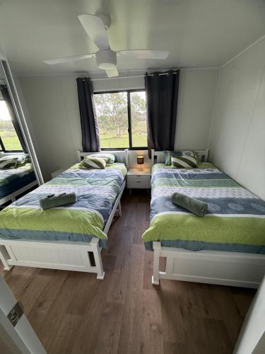 a room with two beds and a window at Peaceful Farm Retreat - Luxury Cabins in Goulburn in Norwood