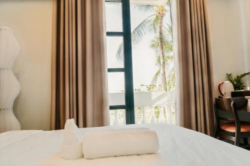a bedroom with a bed and a window with a palm tree at The Happy Marina Hotel Phú Quốc - Sunset & Ocean View in Phú Quốc