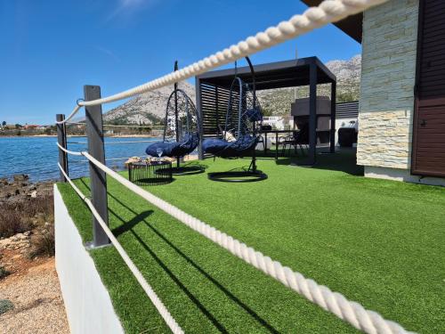 a playground with swings on the grass next to the water at Beach apartment Paklenica-Deluxe in Seline