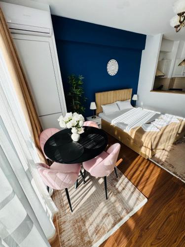 a bedroom with a table and pink chairs and a bed at Luxury Studio Mamaia Nord in Mamaia Sat/Năvodari
