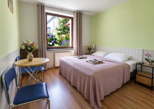 a bedroom with a bed and a table and a window at Pokoje Gościnne Sonia in Tuszyn