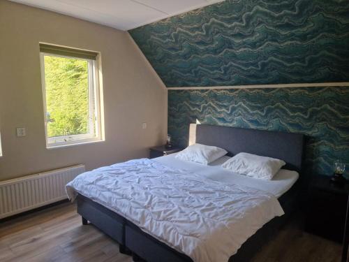 a bedroom with a large bed with a green wall at Nes-Tijd in Nes