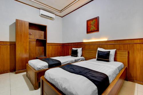 two beds in a room with wood paneling at OYO 3934 Hotel Istana in Pekalongan
