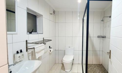 a white bathroom with a toilet and a sink at Point Village Hotel and Self Catering in Mossel Bay
