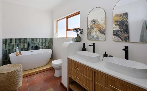 a bathroom with two sinks and a tub and a toilet at Hacienda in Cape Town