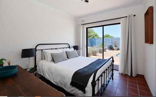 a bedroom with a bed and a sliding glass door at Hacienda in Cape Town