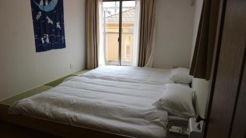 a white bed in a room with a window at Sakuraya 亀島店 in Nagoya