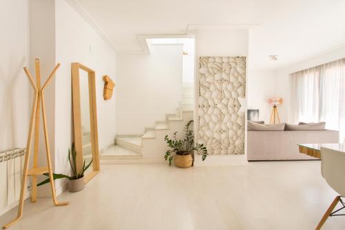 a living room with white walls and a staircase at Realejo Horizon por Miwa Studio in Granada