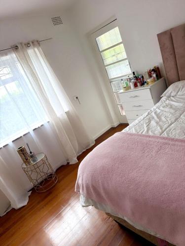 a white bedroom with a bed and two windows at Sonique-Uniqueness Crib in Cape Town