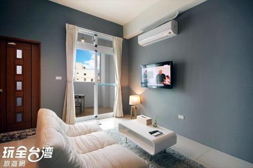 鐵花國小民宿 في مدينة تايتونج: غرفة معيشة مع أريكة بيضاء وتلفزيون