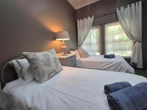 a bedroom with two white beds and a window at 12 On Milner in Kimberley