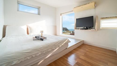 a bedroom with a bed and a tv on the wall at Ganghwa imspa Pension in Incheon