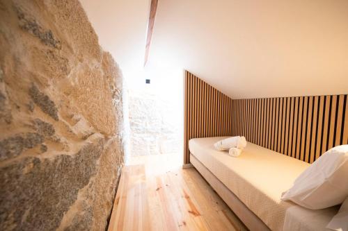 a bedroom with a bed and a stone wall at Villa Santa Bárbara in Vila Nova de Gaia