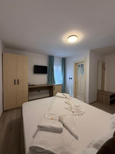 a bedroom with a white bed with towels on it at Pensiunea Miruna Valentin in Jupiter