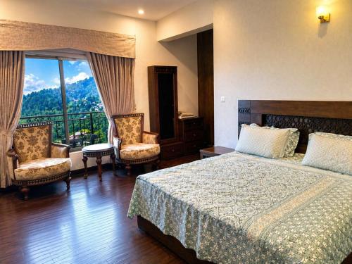 a bedroom with a bed and two chairs and a window at Luxury Noor Villa in Khaira Gali
