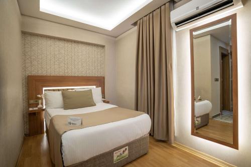 ein Schlafzimmer mit einem großen Bett und einem Spiegel in der Unterkunft Ugurlu Hotel in Gaziantep