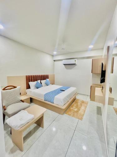 a bedroom with a bed and a couch and a chair at Hotel Sulin Prahladnagar in Ahmedabad