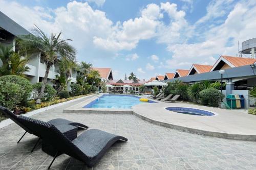 a resort swimming pool with two chairs next to a building at Maharajah Hotel Angeles City in Angeles