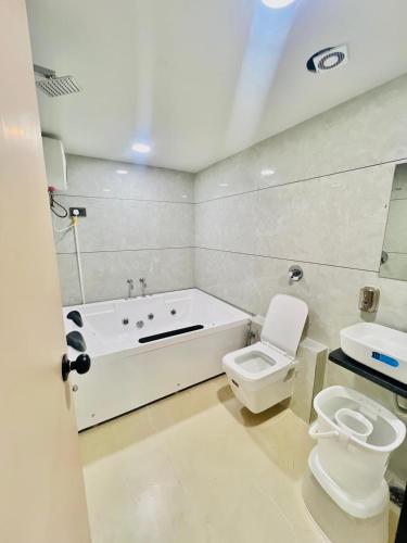 a bathroom with a tub and a toilet and a sink at Hotel Sulin Prahladnagar in Ahmedabad